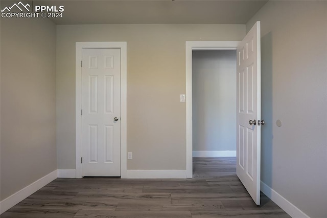 unfurnished bedroom featuring a closet and dark wood-type flooring