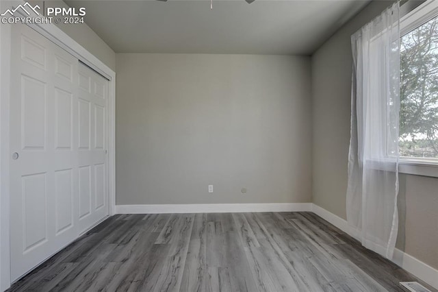 unfurnished bedroom featuring hardwood / wood-style floors, a closet, and multiple windows