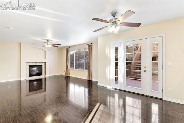 unfurnished living room with dark hardwood / wood-style floors, ceiling fan, and a tiled fireplace