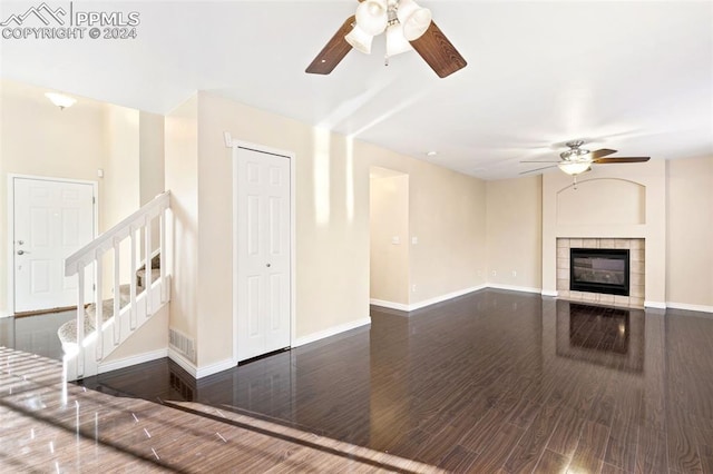 unfurnished living room with a fireplace, ceiling fan, and dark hardwood / wood-style flooring