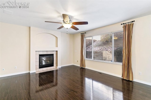 unfurnished living room with a tile fireplace, ceiling fan, and dark hardwood / wood-style flooring