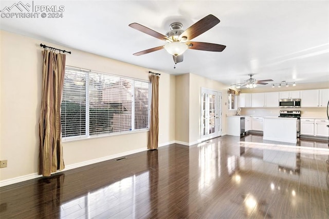 unfurnished living room featuring dark hardwood / wood-style floors, ceiling fan, and sink