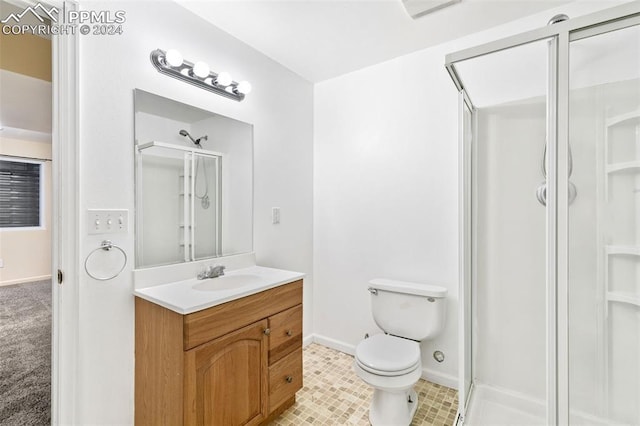 bathroom featuring a shower with door, vanity, and toilet