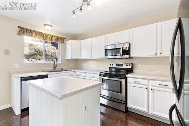 kitchen with appliances with stainless steel finishes, white cabinetry, a kitchen island, and sink