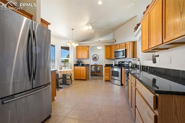 kitchen with stainless steel appliances, dark stone counters, a chandelier, vaulted ceiling, and decorative light fixtures