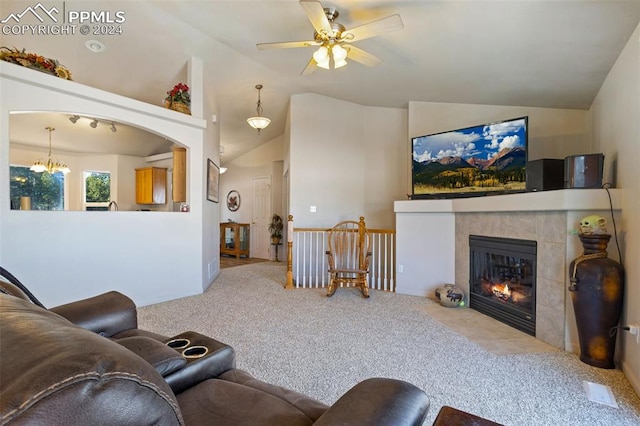 carpeted living room featuring ceiling fan with notable chandelier, lofted ceiling, and a tiled fireplace