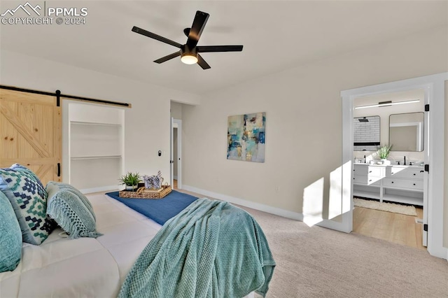 bedroom with ceiling fan, a barn door, and carpet floors