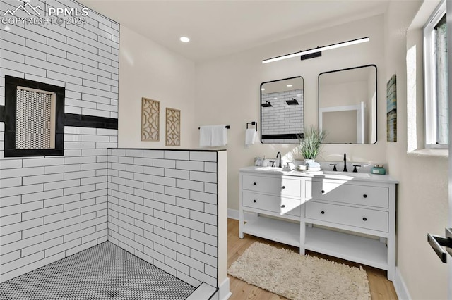 bathroom with hardwood / wood-style floors, vanity, and tiled shower