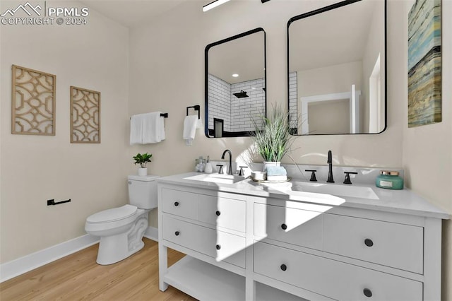 bathroom featuring wood-type flooring, vanity, a tile shower, and toilet