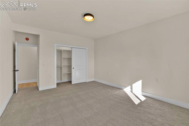 unfurnished bedroom featuring light colored carpet and a closet