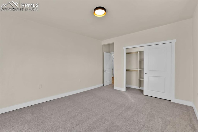 unfurnished bedroom featuring light carpet and a closet