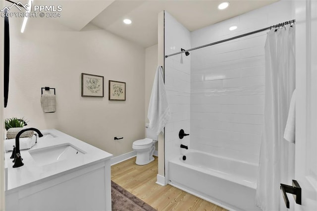 full bathroom with shower / bath combo with shower curtain, hardwood / wood-style floors, vanity, and toilet