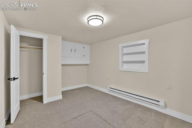 unfurnished bedroom with a closet, light colored carpet, a textured ceiling, and a baseboard heating unit