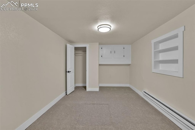 carpeted spare room with a textured ceiling and a baseboard radiator