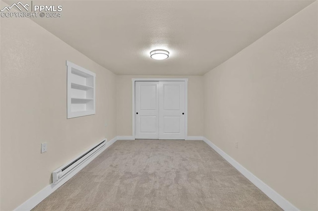 carpeted spare room featuring a baseboard radiator and built in features