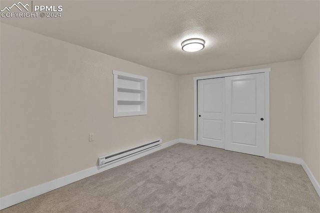 unfurnished bedroom featuring a textured ceiling, light colored carpet, a closet, and a baseboard heating unit