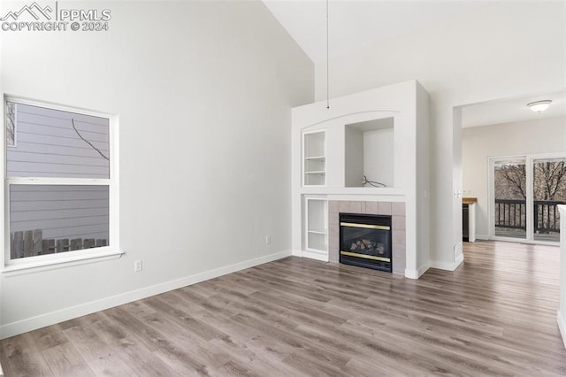 unfurnished living room with hardwood / wood-style floors, vaulted ceiling, and a tiled fireplace