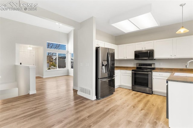 kitchen featuring sink, hanging light fixtures, appliances with stainless steel finishes, light hardwood / wood-style floors, and white cabinetry