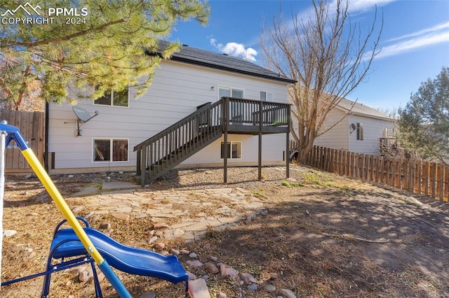 back of property with a playground and a wooden deck