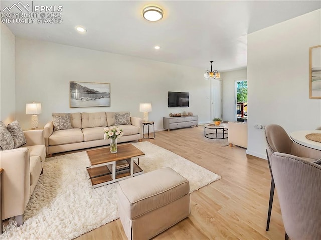 living room with light hardwood / wood-style floors and a notable chandelier