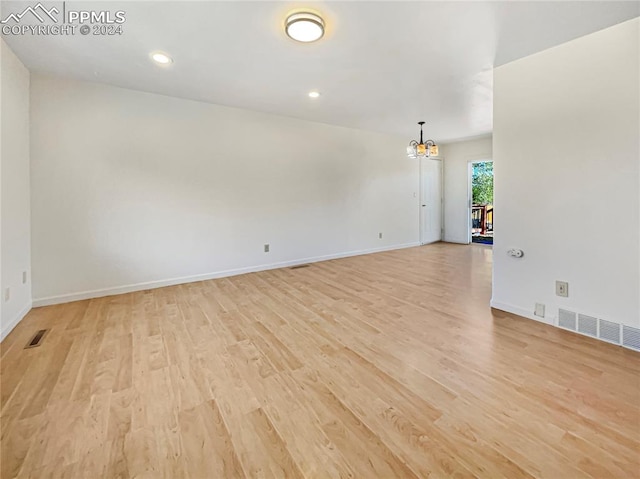 spare room with light hardwood / wood-style flooring and a notable chandelier