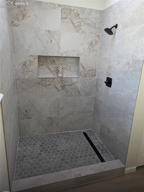 bathroom featuring hardwood / wood-style floors and a tile shower