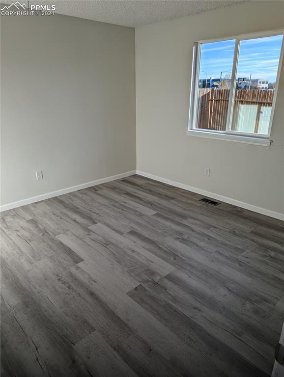 spare room featuring hardwood / wood-style floors and a textured ceiling