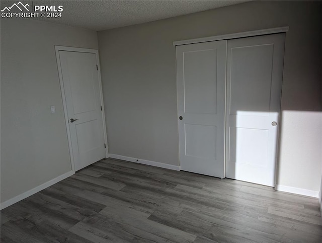 unfurnished bedroom with a closet, wood-type flooring, and a textured ceiling