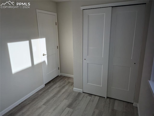 unfurnished bedroom featuring light wood-type flooring and a closet