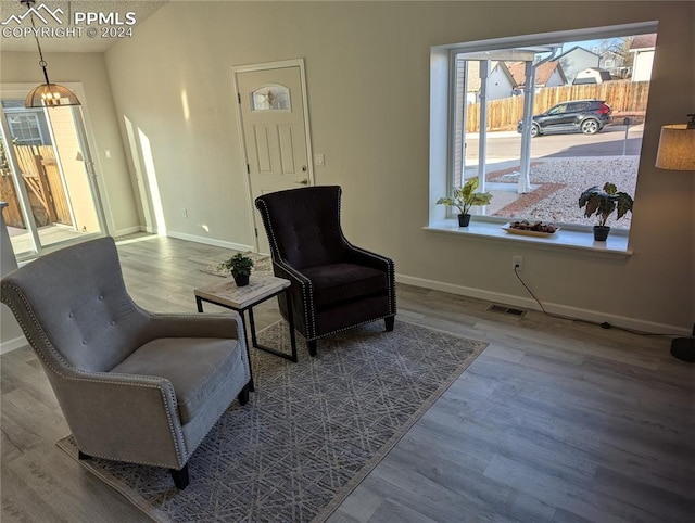 sitting room with hardwood / wood-style floors and an inviting chandelier