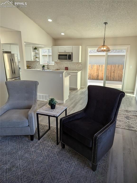 interior space featuring a textured ceiling, dark wood-type flooring, lofted ceiling, and sink