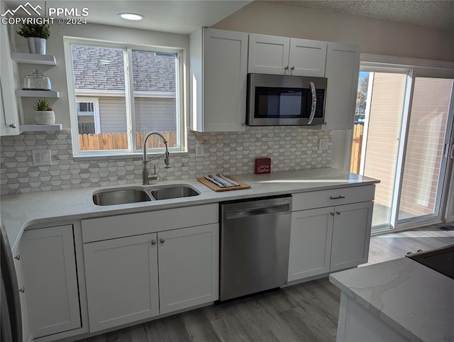 kitchen with sink, white cabinets, stainless steel appliances, and light wood-type flooring