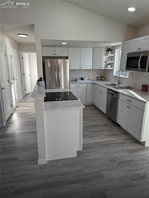 kitchen featuring stainless steel appliances, sink, hardwood / wood-style flooring, white cabinetry, and lofted ceiling