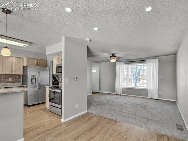 kitchen featuring pendant lighting, light wood-type flooring, a textured ceiling, and appliances with stainless steel finishes