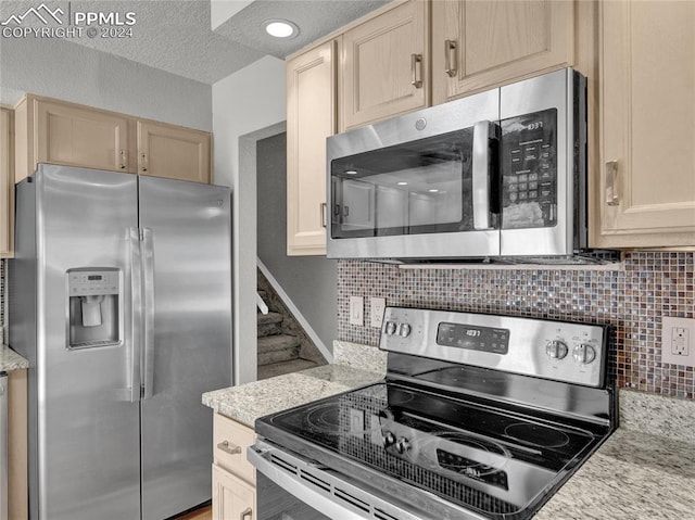 kitchen featuring a textured ceiling, decorative backsplash, light brown cabinets, and stainless steel appliances