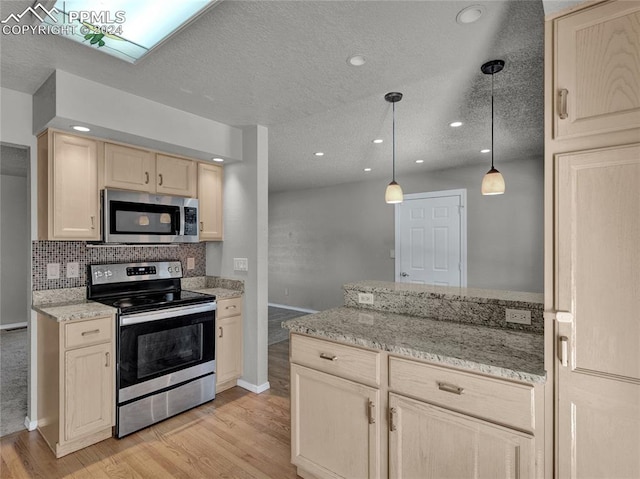 kitchen featuring light stone counters, a textured ceiling, stainless steel appliances, light hardwood / wood-style floors, and hanging light fixtures