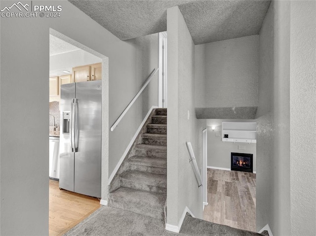 staircase with hardwood / wood-style floors and a textured ceiling