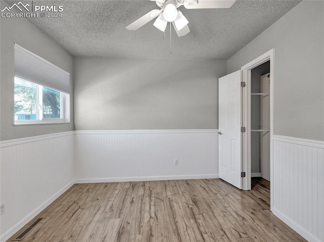 unfurnished bedroom featuring a textured ceiling, light hardwood / wood-style floors, and ceiling fan