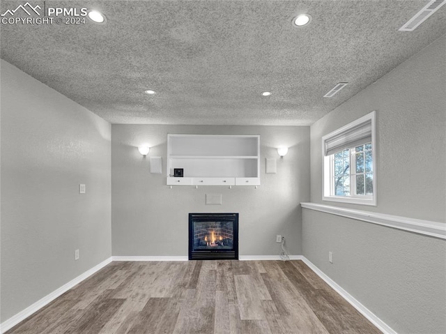 unfurnished living room featuring hardwood / wood-style floors and a textured ceiling