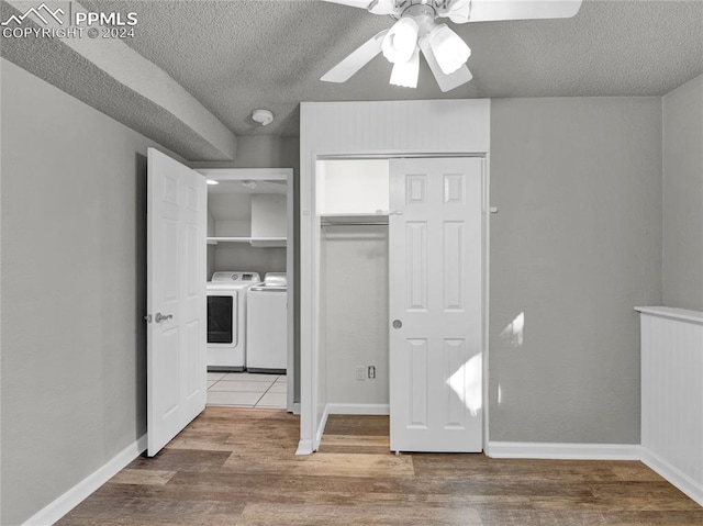 unfurnished bedroom with washer and clothes dryer, ceiling fan, hardwood / wood-style floors, and a textured ceiling