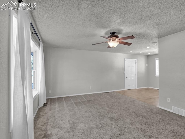 carpeted spare room with ceiling fan and a textured ceiling