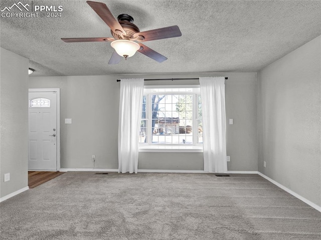 empty room with ceiling fan, carpet floors, and a textured ceiling