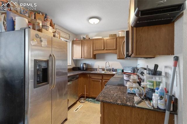 kitchen featuring dark stone countertops, sink, stainless steel appliances, and ventilation hood