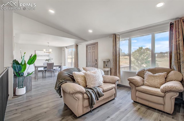 living room featuring a chandelier, light hardwood / wood-style floors, and lofted ceiling