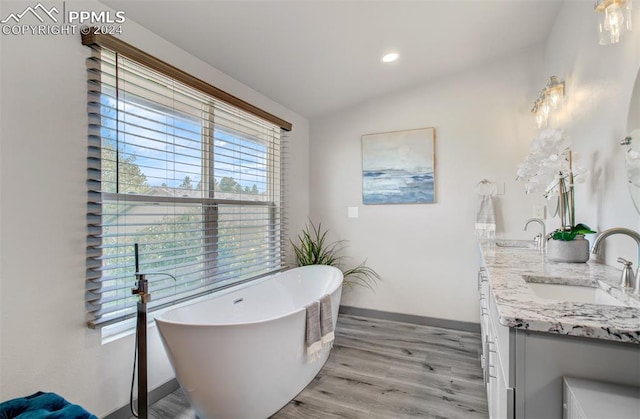 bathroom with hardwood / wood-style flooring, vanity, lofted ceiling, and a bath