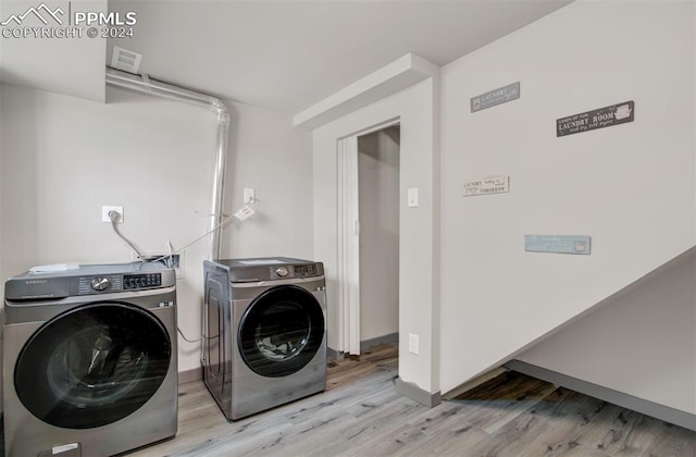 clothes washing area with separate washer and dryer and light wood-type flooring