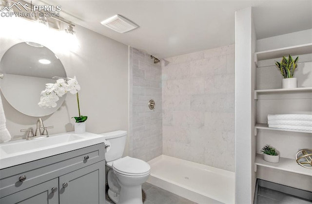 bathroom with tile patterned flooring, vanity, tiled shower, and toilet