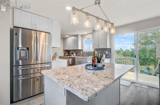 kitchen featuring a center island, stainless steel fridge with ice dispenser, backsplash, light hardwood / wood-style floors, and white cabinets