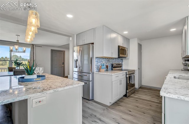 kitchen with white cabinetry, stainless steel appliances, decorative light fixtures, and light hardwood / wood-style floors