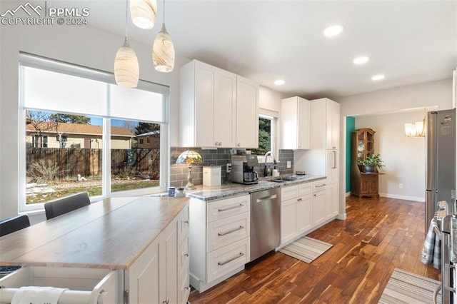 kitchen featuring stainless steel dishwasher, a healthy amount of sunlight, and white cabinetry